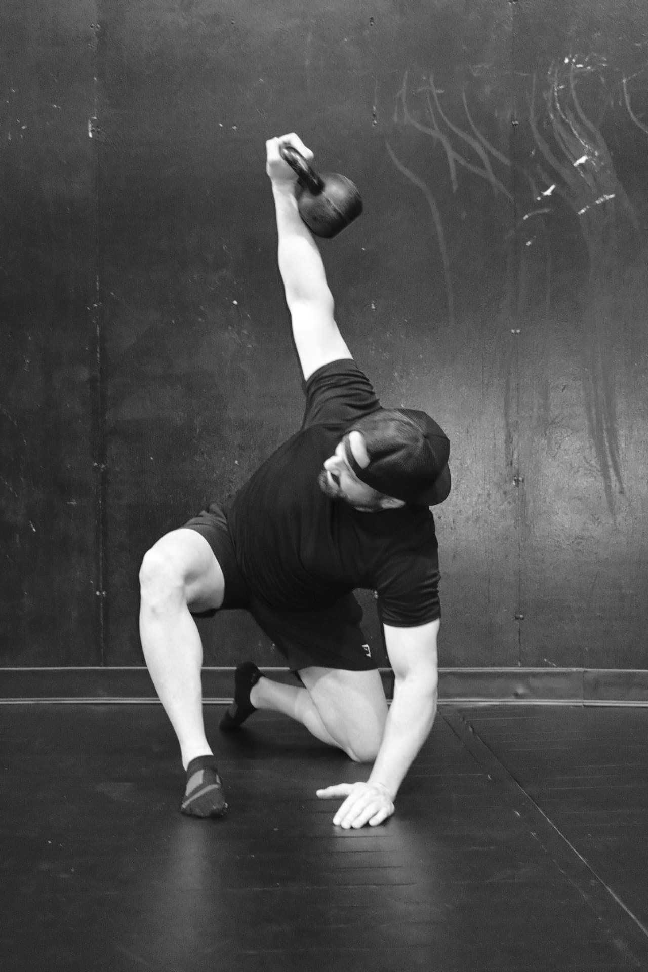 Black and white photo of Shawn Taylor kneeling on one knee with a kettlebell held overhead