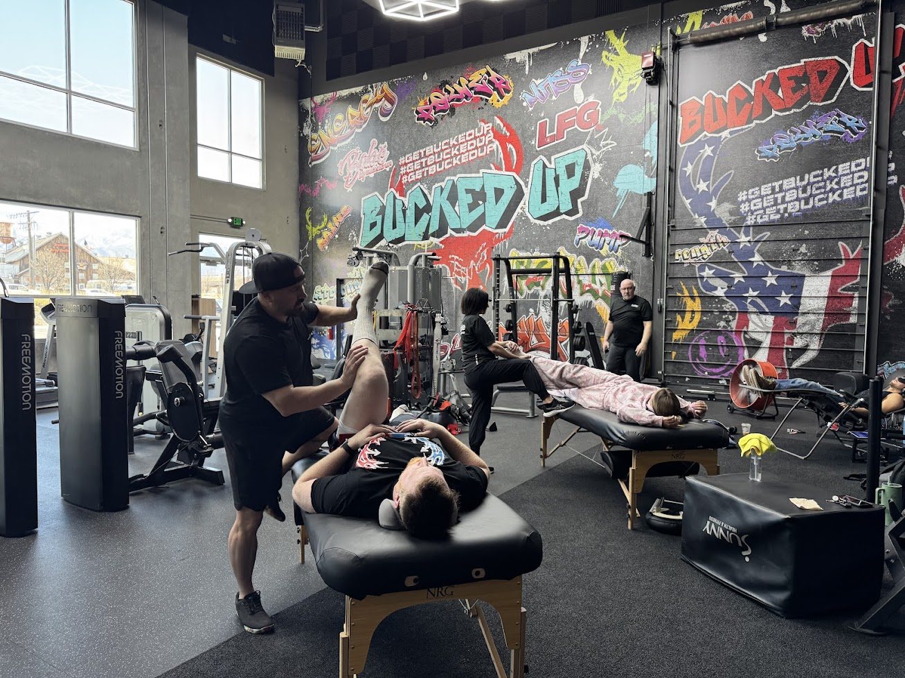 Shawn Taylor stretching a client on a table inside the Bucked Up gym during a group recovery event